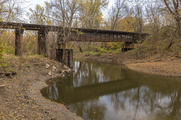 Railroad Bridge Crossing River In Thee Woods
