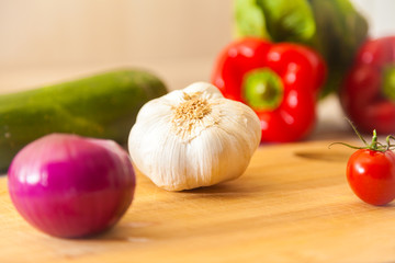 white garlic lies on a board with other vegetables