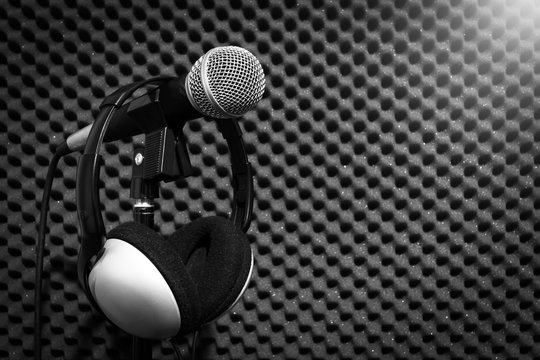 microphone & headphone on acoustic board background in recording studio