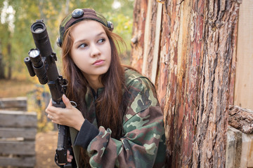 Fototapeta premium Young girl with a gun peeking from behind cover