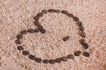 Heart shape made from coffee beans on  on sand