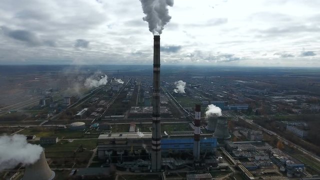 Ecology pollution. Industrial factory pollutes the environment blowing smoke from pipes. 4K. Aerial.