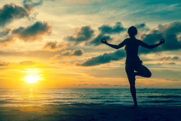 Fototapeta na wymiar Silhouette woman practicing yoga on the coast during a fantastic sunset.