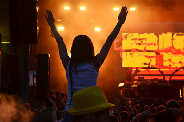 Obraz na płótnie Canvas Girls with hands up dancing, singing and listening the music during concert show on summer music festival