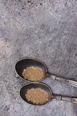 Silver spoonfuls with brown sugar on metal table top view