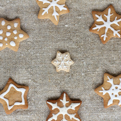  holiday background with cakes/ gingerbread cookies with Glaze in the form of stars and snowflakes lay on linen cloth top view 