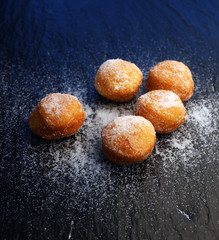 German donuts - berliner with jam and icing sugar in a tray on a dark wooden background.