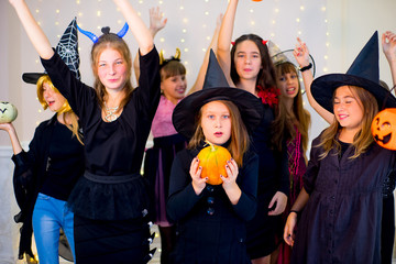 Happy group of teenagers dance in Halloween costumes