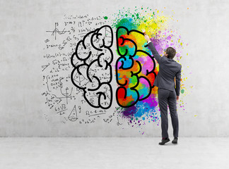 Rear view of businessman drawing colorful brain icon on concrete