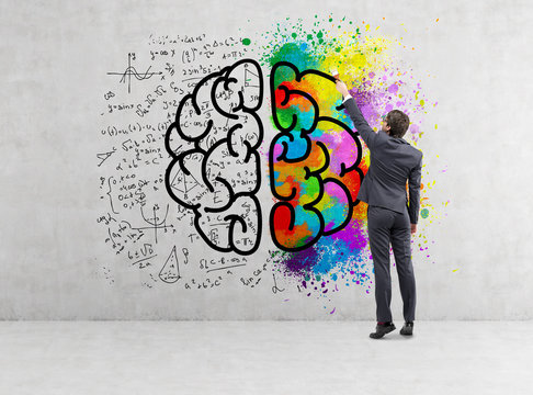 Rear view of businessman drawing colorful brain icon on concrete