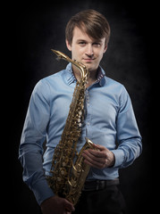 Naklejka premium Attractive saxophonist on a dark background.