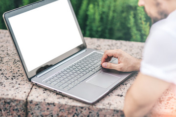 Man working on modern Laptop mockup with white blank screen. Close up of man's hands touching touchpad
