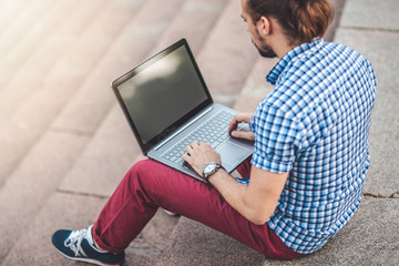 Naklejka premium Young Man with Laptop sitting on the stairs