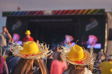 Girls on summer music festival listen music in front of stage with yellow hat on head. Original summer wallpaper with free space for own title or quote