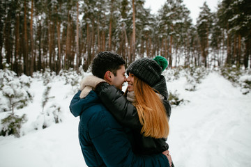 Fototapeta na wymiar Couple in winter clothes walking in a snowy forest. Winter Love story.