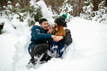 Fototapeta na wymiar Couple fooling around in the snow under the tree.