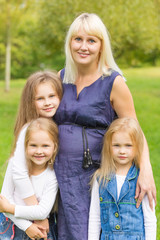 Fototapeta premium Young pregnant mother with her daughters in a park