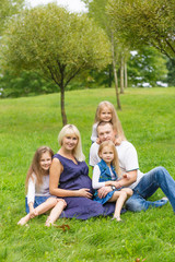 Fototapeta premium Young pregnant mother with her family in a park