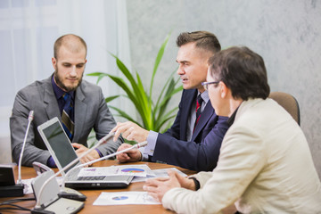 
Modern managers listening to speaker at conference or seminar, young businessman sitting in office and working with laptop 