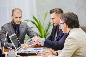
Modern managers listening to speaker at conference or seminar, young businessman sitting in office and working with laptop 