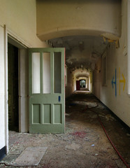 Open door in old abandoned asylum corridor
