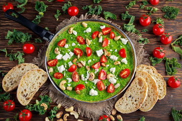 Vegetables Green Omelette with tomatoes, kale, greek cheese, olives, nuts, toast on wooden background. concept healthy food