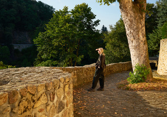 Man shading his eyes with his hands watching a wooded valley on the historic stone terrace with a...