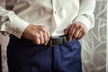 Obraz na płótnie Canvas man putting on a belt, Businessman, Politician, man's style, male hands closeup, American businessman, European businessman, a businessman from Asia, People, business, fashion and clothing concept