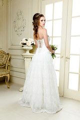 Fototapeta premium Gorgeous bride in luxury wedding dress. Bride. Perfect Make up. Hairstyle, wedding jewelry. Beautiful Woman with Shiny Brown Hair. gorgeous wedding bouquet of various flowers.
