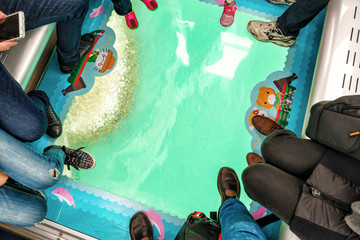 Naklejka premium Ocean shore viewed through the transparent glass floor of a Crystal Cabin, Ngong Ping Skyrail on Lantau Island, Hong Kong