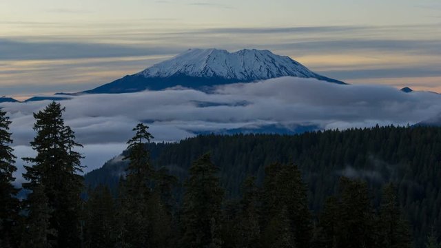 Time lapse of moving clouds and rolling low fog over beautiful snow covered mount st. helens in Washington state at sunset 4k uhd