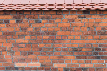 Texture of brick wall finished with red roof. 