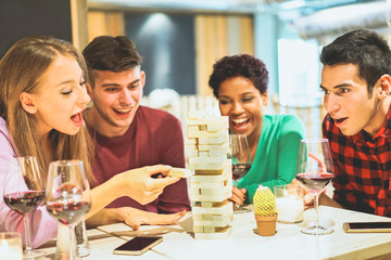 Group of young friends having fun playing board game in pub wine bar