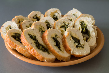 Chicken rolls with spinach and cheese on orange plate.