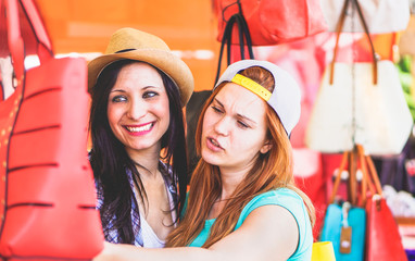 Young cheerful women at flea market buying fashion bags