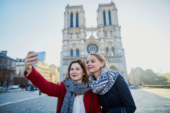Two young girls taking selfie near Notre-Dame in Paris