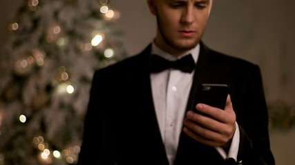 Young handsome man in stylish suit, chatting on mobile phone on New Year day.