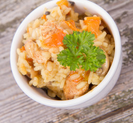 Risotto with chicken, bell pepper, onion, portobello and parsley on a wooden background