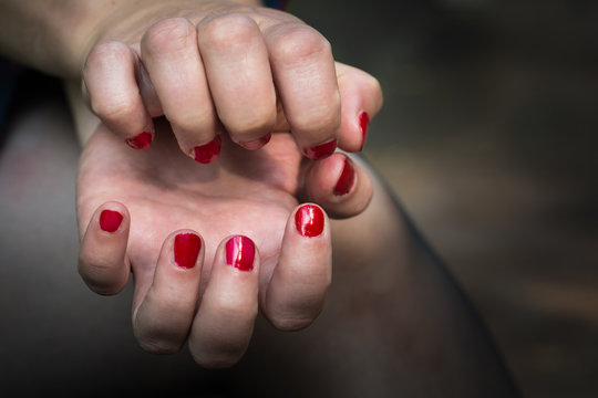 Women bent fingers of both hands facing each other. The nails are painted with red lacquer.
