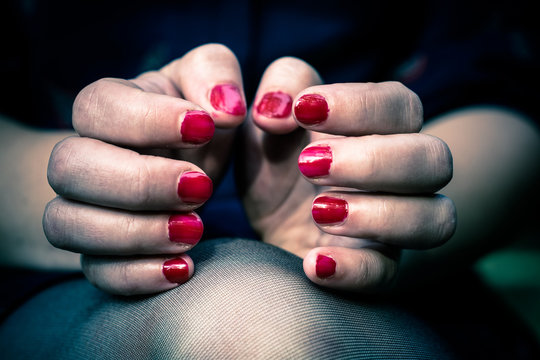 Women bent fingers of both hands facing each other. The nails are painted with red lacquer.

