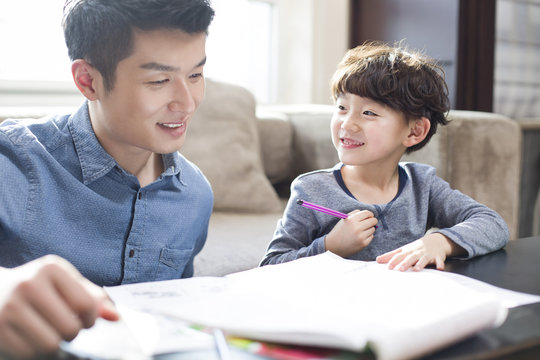 Father helping son while doing homework