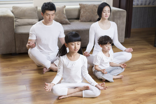 Young Family Doing Yoga At Home