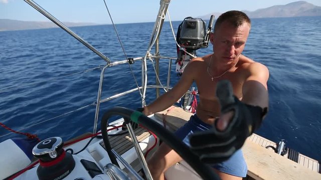 Man Skipper on yacht pulls the rope during drives the sailing boat.