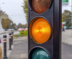 Yellow traffic light in the city street close