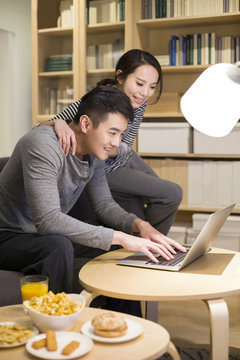 Young couple using laptop in living room