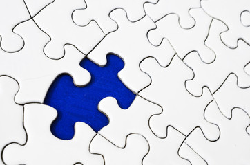 A top view image of a white jigsaw puzzle with a missing piece.