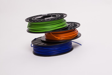 Top view of blue, orange and green 3D printer filament spools stacked off-center 