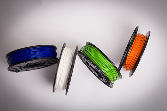 Bird view of blue, white, green and orange 3D printer filament spools loosely arranged