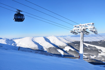 Fototapeta premium Chairlift over winter landscape in wonderful mountains full of snow