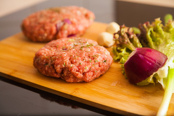 raw meat burger lies on a board